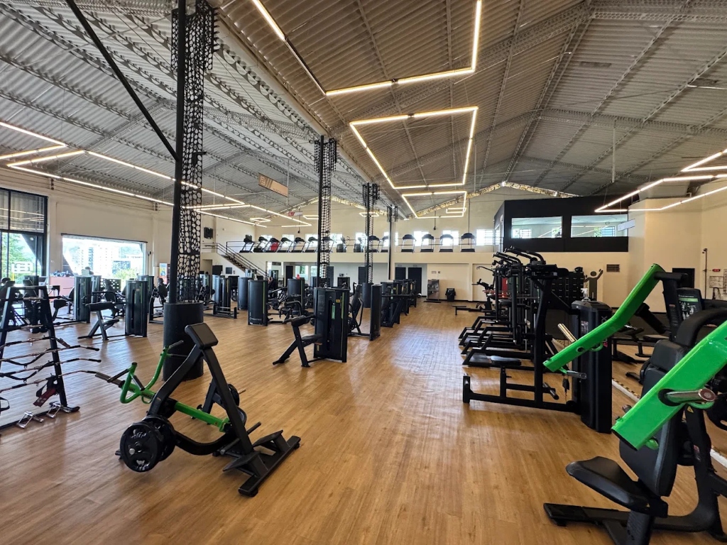 Aparelhos de musculação modernos com iluminação de teto geométrica na Academia Futuro